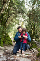 Father teaching photography to  his little daughter during a hiking day in a pyrenean forest.