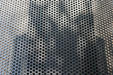 Metal mesh, background, with round identical holes, metal structure with shadow and light.