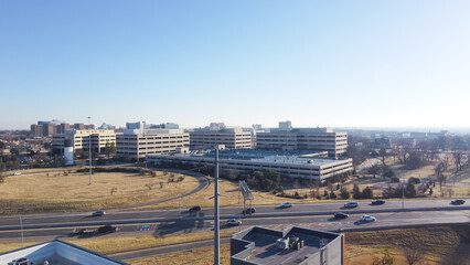 Large college campus near I-235 Highway loop with office buildings and rooftop parking garage, busy...