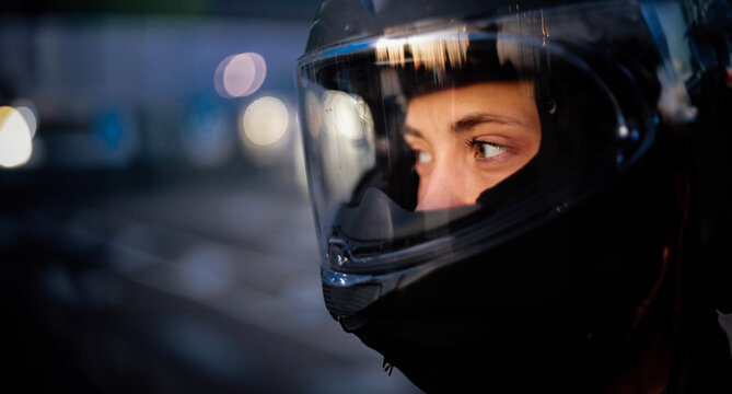 female motorcyclist close-up in a helmet in the evening on a motorcycle in the city.