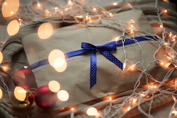 A gift envelope made of kraft paper with a blue ribbon. The New Year's gift is wrapped in garlands....
