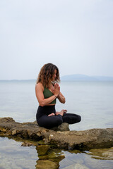 Fototapeta na wymiar Woman practicing yoga by the sea on the rocks