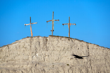 Three crosses on a hill with a vulture flying in the foreground in the Tatacoa Desert in Huila, Colombia
