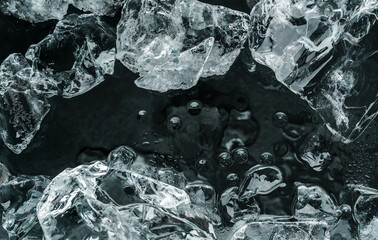 Pieces of crushed ice on black background. Abstract ice structure background, top view