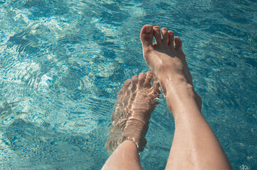 beautiful woman feet in pool water.