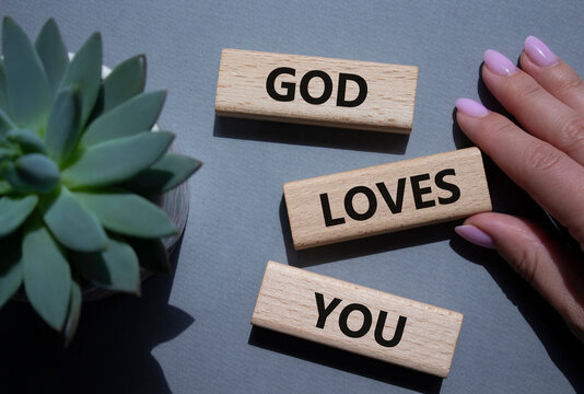 God loves you symbol. Wooden blocks with words God loves you. Beautiful grey background with succulent plant. Prayer hand. Religion and God loves you concept. Copy space.