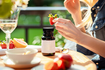Beautiful smiling woman taking vitamin pills for breakfast. Food supplement. A plastic bottle with vitamins stands in the foreground on the table. balanced diet, healthy nutrition. mock up - obrazy, fototapety, plakaty