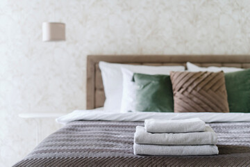 Clean terry towels folded on bed with blanket and cushions in modern hotel room