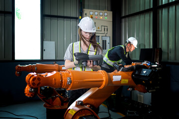 Fototapeta premium Factory engineers inspecting on machine with smart tablet. Worker works at heavy machine robot arm. The welding machine with a remote system in an industrial factory. Artificial intelligence concept.
