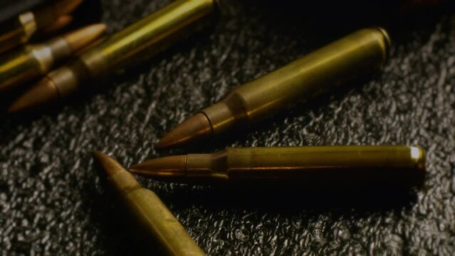 Machine Gun Bullets Close Up Ammunition Zoom Out. Zoom out from a few bullets huddled together in a cartridge. Tracking shot