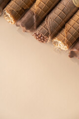 Waffle tubes with chocolate or nuts on beige background with copy space
