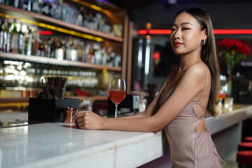 beautiful Asian woman orders a drink to relax and drink soft drinks behind the counter bar in a restaurant