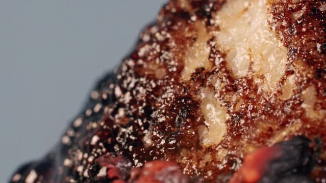 An ignited meal burns and melts in the flame, blows bubbles and boils in the smoke, isolated on the grey background. A red hot dish is undergoing intensive frying and heat treatment. Close up.