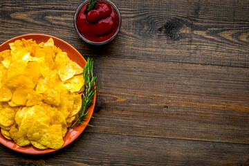 Homemade potato chips with ketchup for snack on wooden background top view copyspace