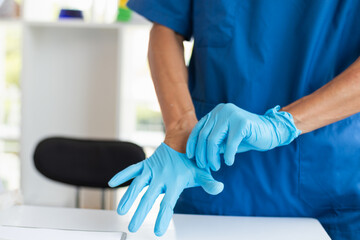 doctor is wearing blue rubber gloves prevent direct contact with patient because virus may be...