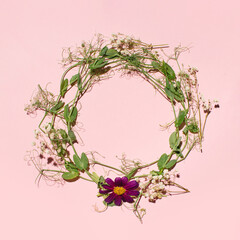 Spring wreath made of colorful flowers and leaves. Natural round floral frame layout with creative copy space, pastel pink background. 