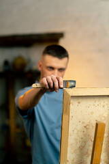 close up in an art workshop an artist in a blue T-shirt makes broad strokes on the canvas with wide...