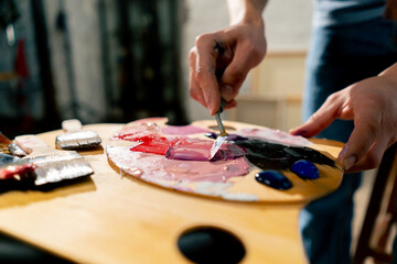 close up in an art studio an artist mixes paint on a palette with a palette knife