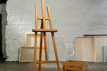 in an art studio there is a tripod against background of canvases next to a box