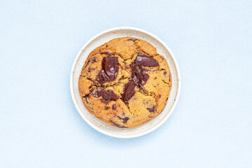 A piece of homemade chocolate chip cookie on ceramic plate.