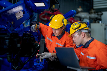Fototapeta premium Factory engineers inspecting on machine with smart tablet. Worker works at heavy machine robot arm. The welding machine with a remote system in an industrial factory. Artificial intelligence concept.