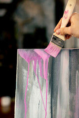 close-up from below in art workshop the artist makes pink streaks on canvas