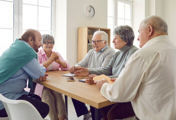 Group of elderly people are talking and having good time together sitting at table at home....