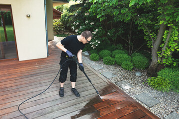 man cleaning terrace with a power washer - high water pressure cleaner on wooden terrace surface - 748141158