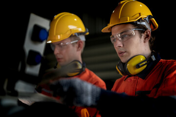 Engineer man checking the status of machine and used wrench to screw some part of equipment at CNC factory. Worker wearing safety glasses and helmet. Maintenance and repairing concept.