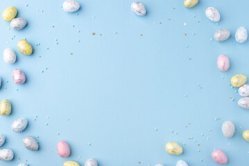 Festive Easter background. Multicoloured Easter eggs on a blue table. Banner with a place for text. Top view.