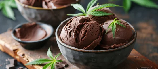  A bowl of creamy chocolate ice cream topped with a distinct marijuana leaf. This dessert option is infused with THC or CBD, providing a smoke-free cannabis edible experience. © 2rogan