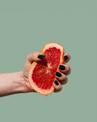 Woman hand holding and squeezing half of the grapefruit