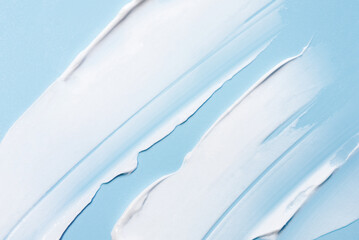 The texture of the skin or hair care product. White smear of cream, mask or balm on a blue background.