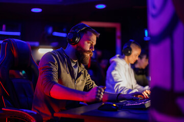 Bearded male eSports gamer playing online strategy video game ina gameroom