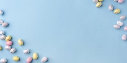 Festive Easter background. Multicoloured Easter eggs on a blue table. Banner with a place for text. Top view.