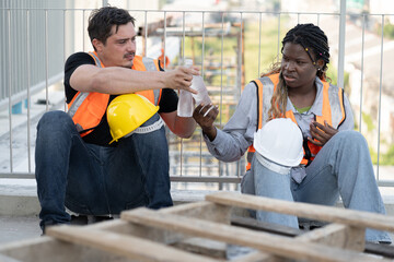 Portrait very tired worker African woman and caucasian man with holding water bottle at...