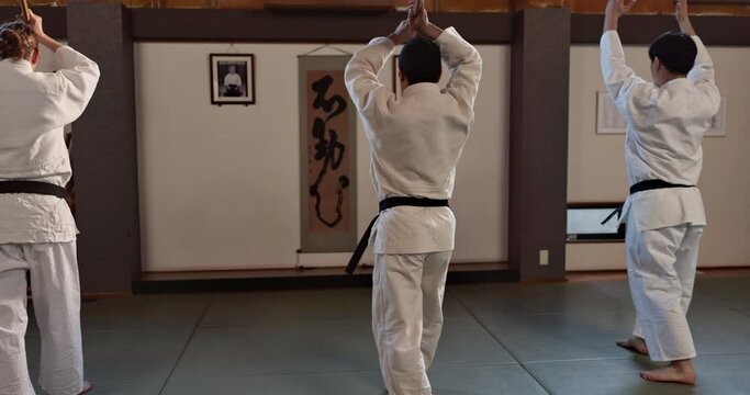 Japanese students, stick or learning martial arts in dojo for practice, aikido movement or self defense. Combat demonstration, fitness or people training workout for fighting, education or class