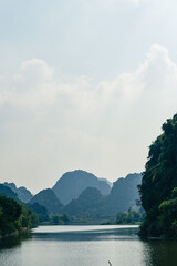 Landscape views of limestone mountains, reflective water and lush greenery of Tran An. A popular...