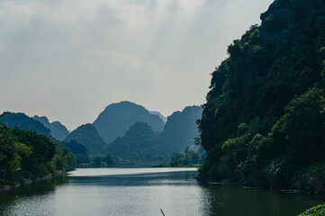 Landscape views of limestone mountains, reflective water and lush greenery of Tran An. A popular...