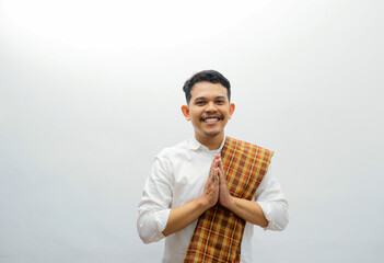Asian Muslim man wearing white clothes  and sarung smiling to give greeting during Ramadan and Eid...
