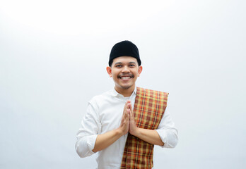 Asian Muslim man wearing white clothes  and sarung smiling to give greeting during Ramadan and Eid...