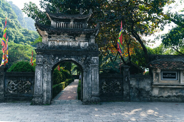 A stone gate with an open door to a manicured buddhist garden and temple