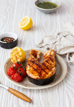 Grilled salmon steak glazed with teriyaki sauce, tomatoes and lemon