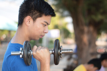 Asian plump young man lifts four-kilogram and eight-kilogram dumbbells to exercise and loose weight...