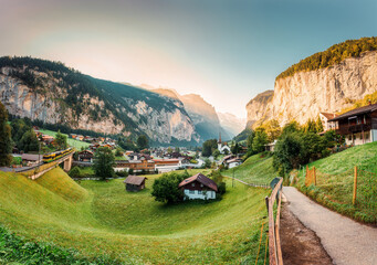 Lauterbrunnen valley with rustic village, famous church and Staubbach falls in the morning at Switzerland