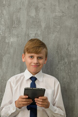 Fototapeta premium a little boy in a shirt with a tie and a tablet in his hand is playing a businessman, financial concept