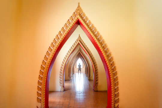 Traditional golden arch door with male tourist in corridor at Wat Tham Sua, Kanchanaburi