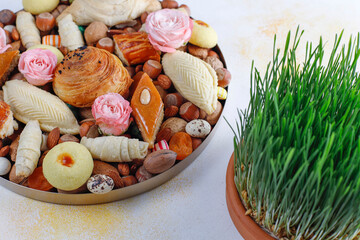 Traditional Azerbaijan holiday Novruz background with green semeni,traditional azerbaijan sweets,shekerbura,qogal,paxlava,mutaki and different nuts and sweets,top view,space for copy