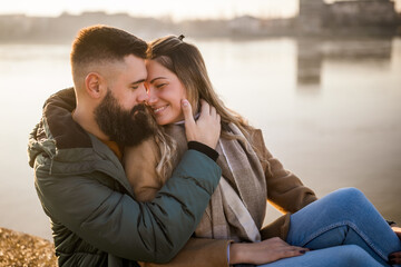 Happy couple embracing while enjoy sitting by the river.	