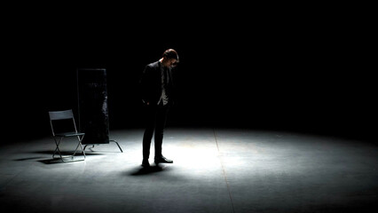 Man in suit alone on theater stage. Stock footage. Single attractive man in suit is playing on stage of theater. Man in suit with mirror is alone on dark theatrical stage